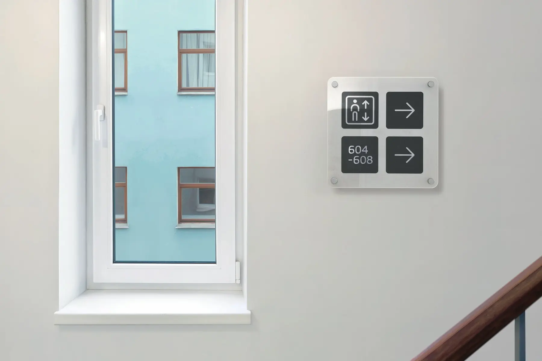 Clinic frosted acrylic wayfinding sign mounted with silver standoffs on white wall