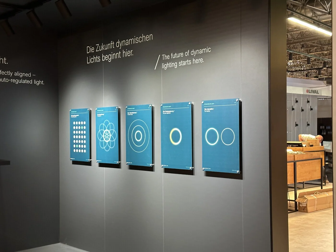 Trade exhibition booth with five acrylic display panels mounted using sign standoffs on dark wall