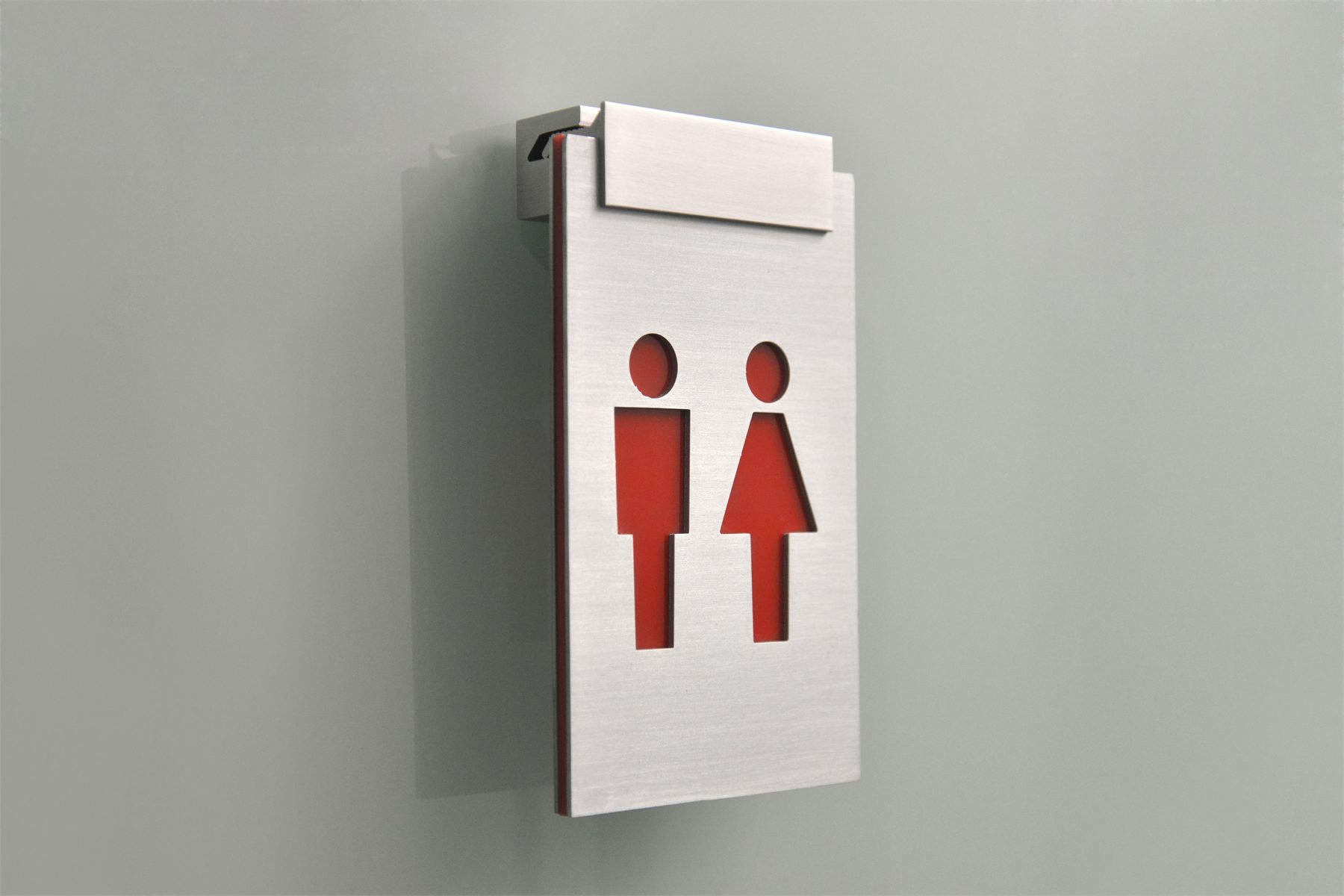 Aluminium sign clamp holding a brushed metal restroom sign panel on glass