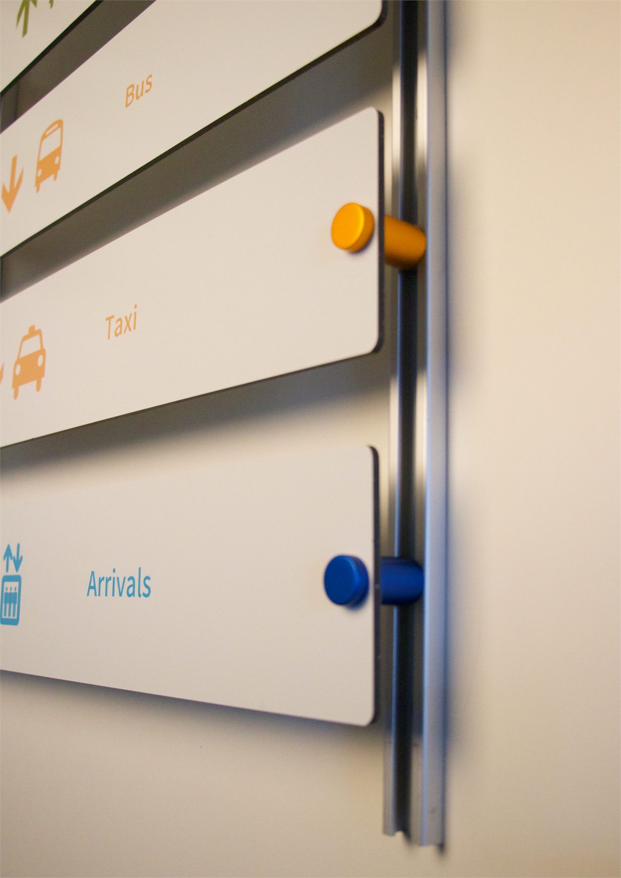 Color-coded sign standoffs mounted on a vertical rail system for changeable wayfinding panels
